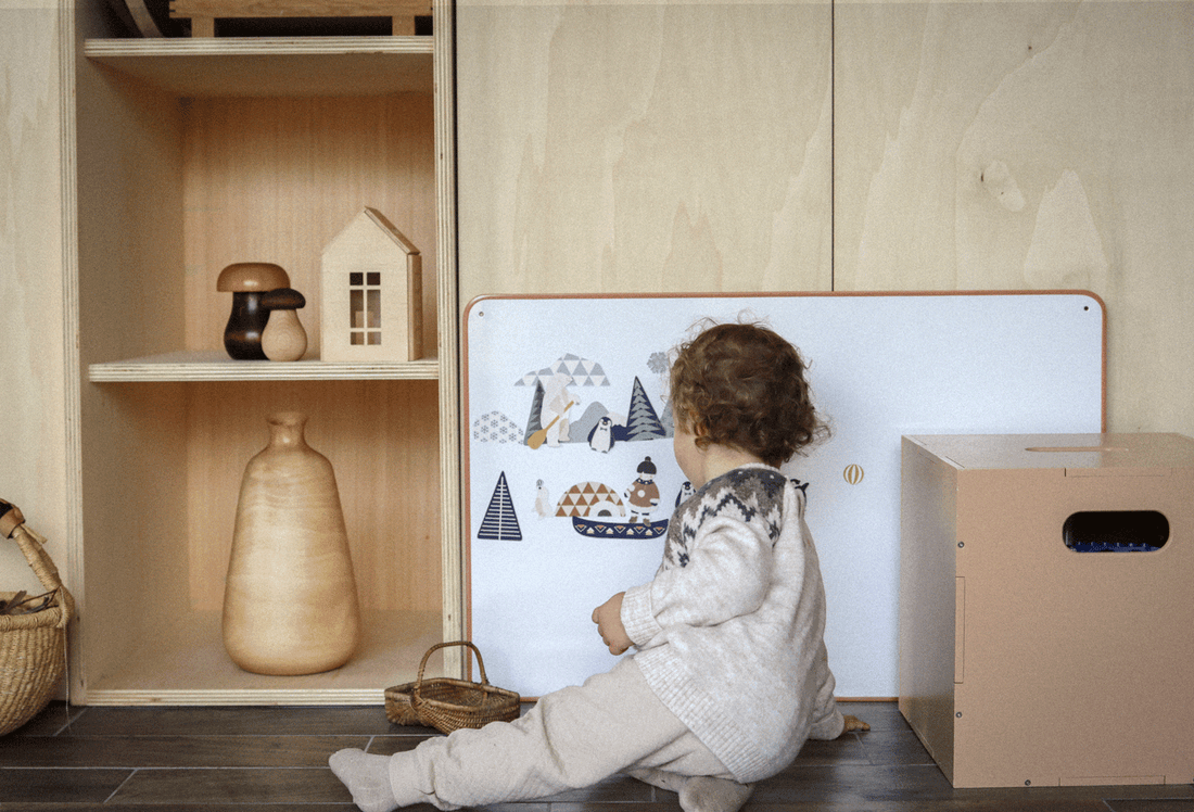 Enfant jouant avec un tableau magnétique bois 30x40cm posé contre un meuble