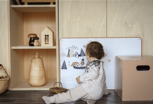 Enfant jouant avec un tableau magnétique bois 30x40cm posé contre un meuble