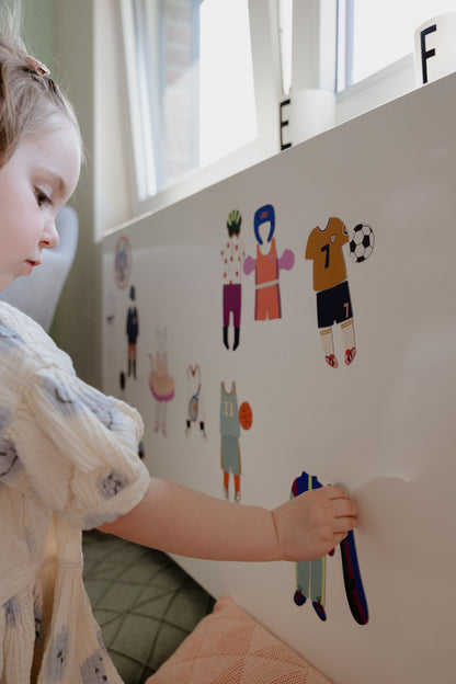 Petite fille jouant au jeu magnétique Les Sports sur un tableau blanc, dès 3 ans