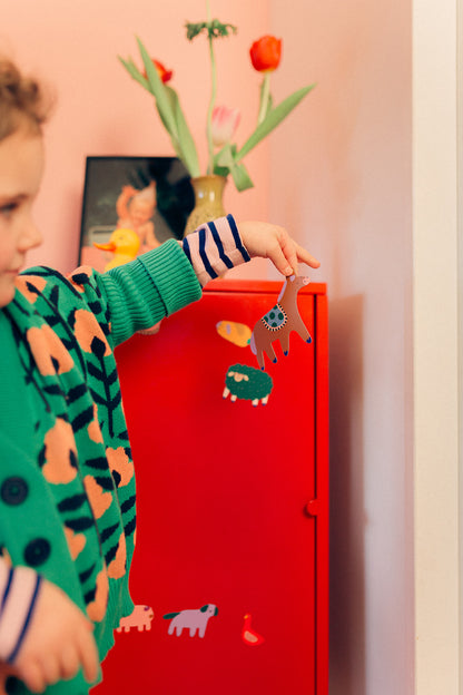 Petite fille jouant avec les magnets Ferme collés sur un meuble rouge