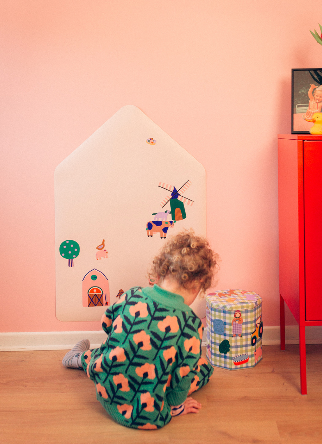 Enfant jouant avec le jeu magnétique Ferme sur un tableau magnétique mural en forme de cabane