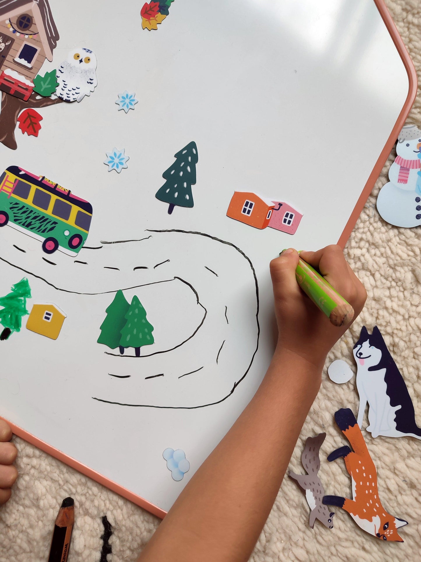 Enfant qui joue avec des magnets et dessine sur un tableau bois magnétique